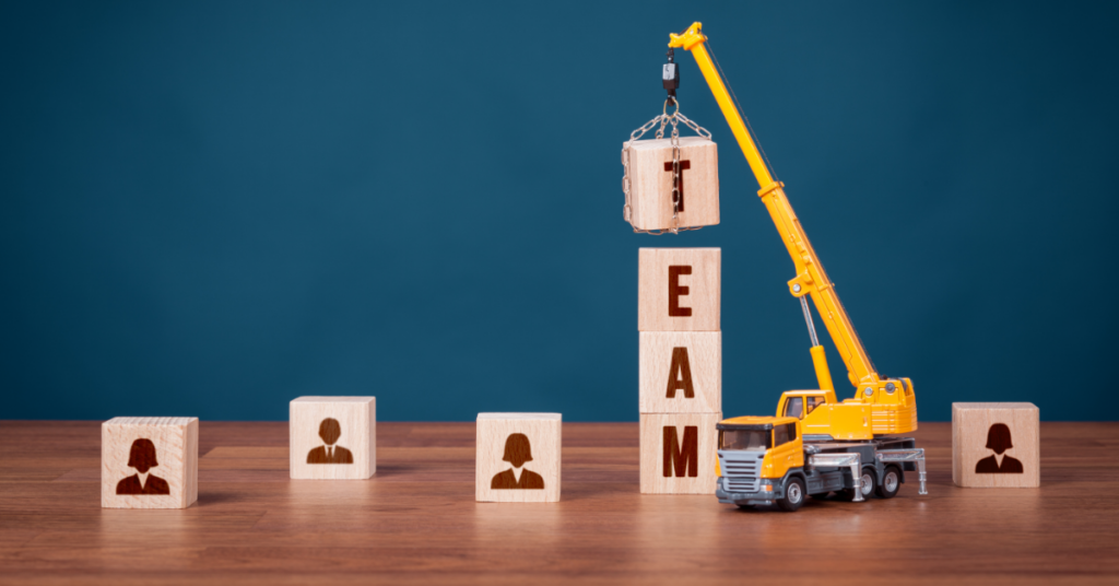Building an Analytics Team in Your Organization. A toy truck putting together blocks spelling out the work team.